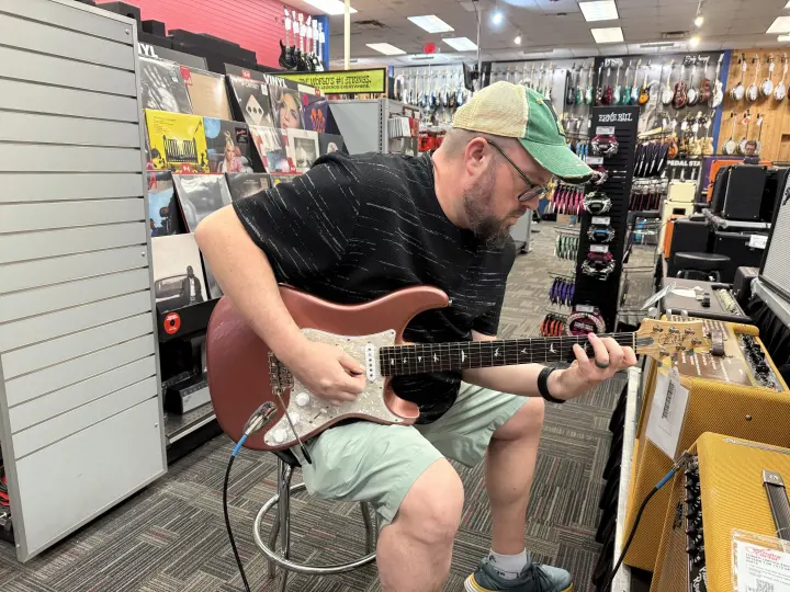 Mike trying out a guitar in a music store