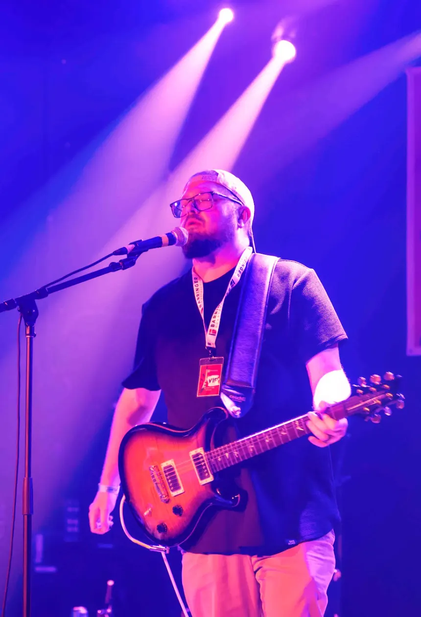 Mike playing guitar on stage under purple lights